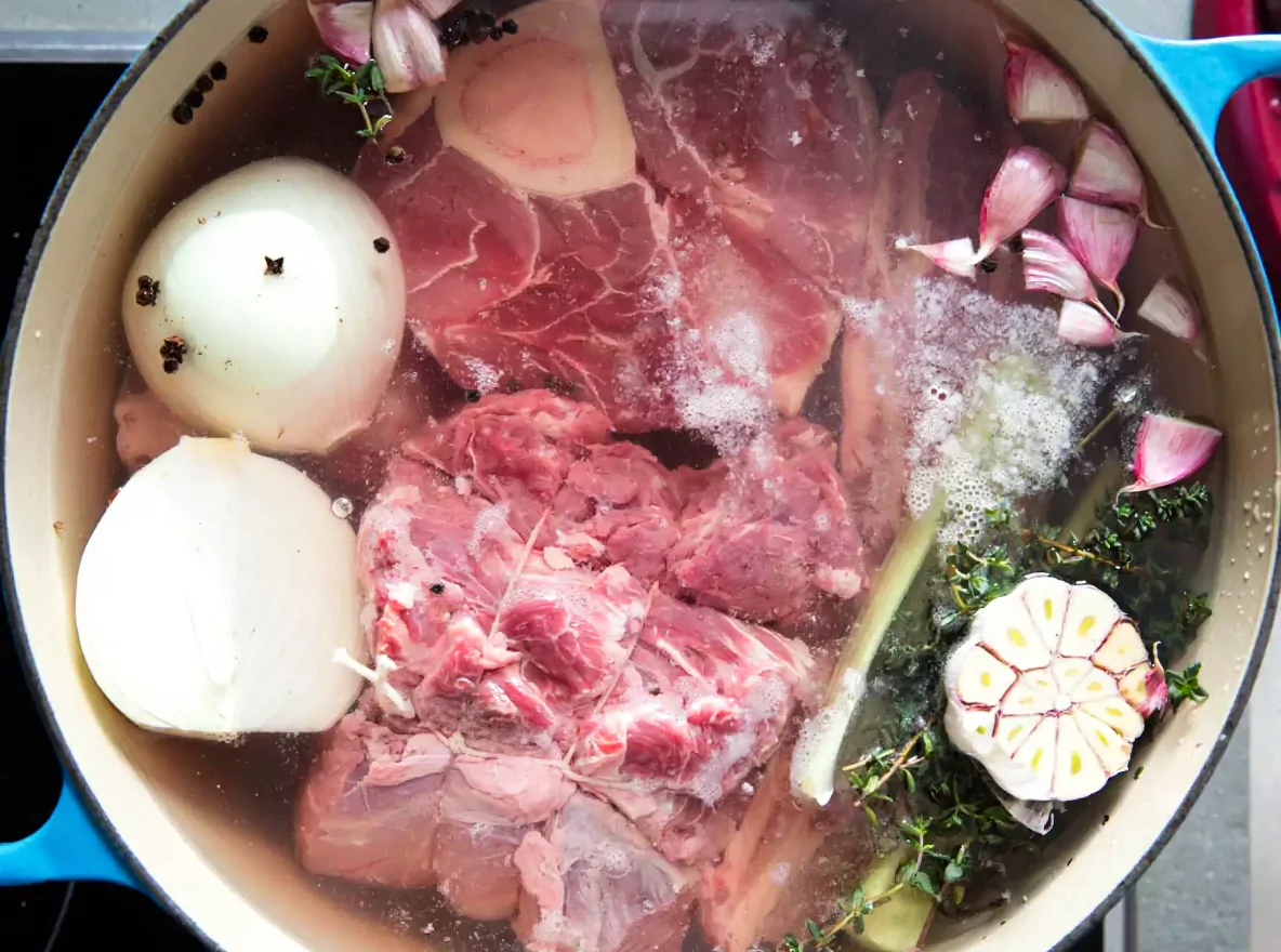 Écumage du bouillon, étape essentielle de la recette pot au feu pour un résultat limpide.