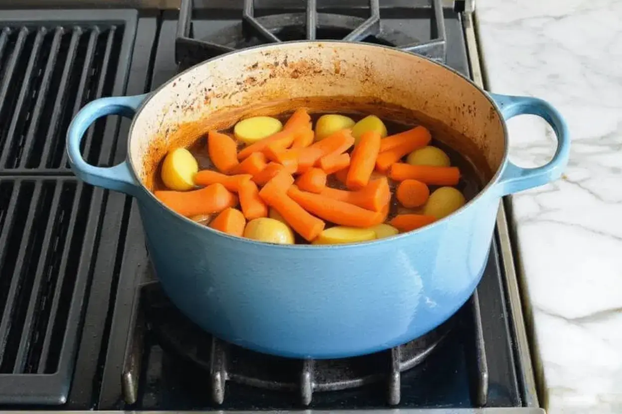 Ajout des carottes et pommes de terre au ragoût avant la cuisson au four
