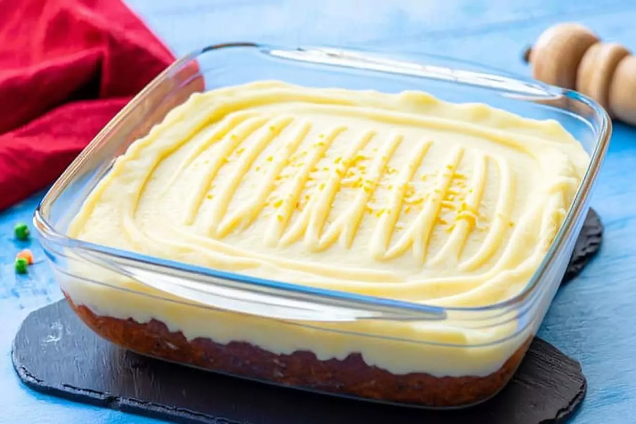 Assemblage du hachis parmentier avec une couche de viande et une couche de purée lissée, recouverte de fromage râpé