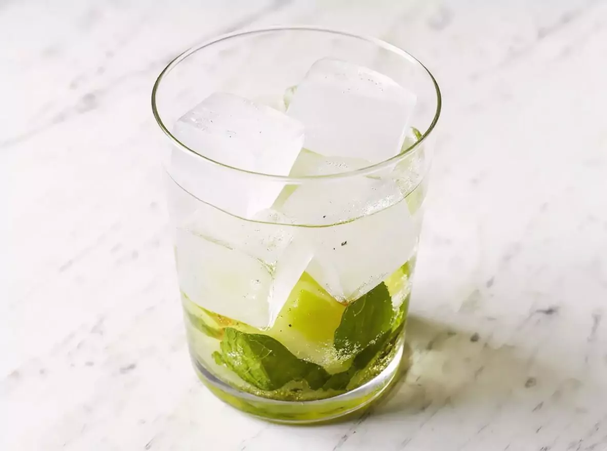Étape 3 mojito : ajout des glaçons dans le verre avec les ingrédients écrasés