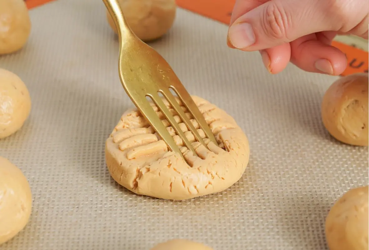 Fourchette créant le motif croisé caractéristique sur les cookies au beurre de cacahuète avant cuisson