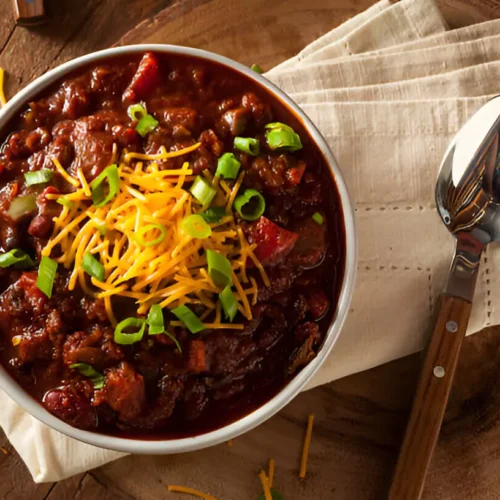 Un bol fumant de notre recette chili cone carne, garni de crème fraîche, fromage et coriandre.