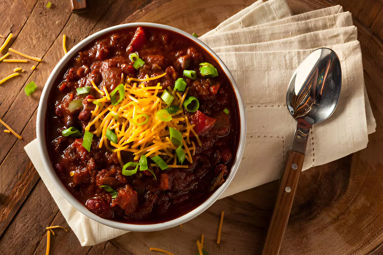 Un bol fumant de notre recette chili cone carne, garni de crème fraîche, fromage et coriandre.
